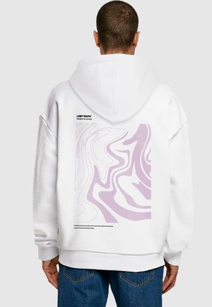 Hvid hættetrøje med grafisk design på ryggen bestående af abstrakte lilla svømme. Inkluderer et sort mærke-logo og plejeinstruktioner nederst.