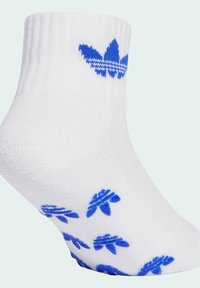 Calza bianca alla caviglia realizzata in un tessuto morbido, con il logo Adidas blu sulla caviglia e motivi a foglia blu ripetuti sulla suola.