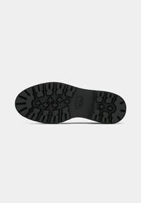 Semelle de chaussure en caoutchouc noir avec un design de semelle robuste comportant de profonds rainures et motifs de traction pour une adhérence améliorée.