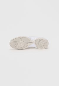 Sola de sapatilha branca com um solado de borracha beige texturizado e padrão de ranhuras visíveis. Apresenta um cabedal branco liso com acentos mínimos.