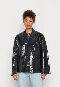 Jaqueta de couro envernizado preto com um design de gola, botões frontais e dois bolsos, apresentando uma textura brilhante e suave e um ajuste oversized.