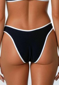 Slip bikini neri con rifiniture bianche; realizzati in materiale elasticizzato, con un design a gamba alta e copertura minima sul retro.