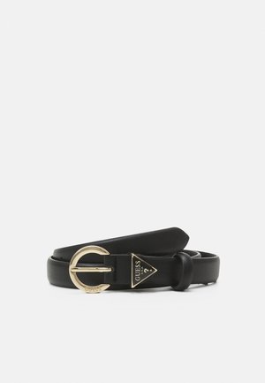 Ceinture en cuir noir avec une boucle ronde dorée et un petit logo triangulaire doré Guess près de la boucle sur fond blanc.