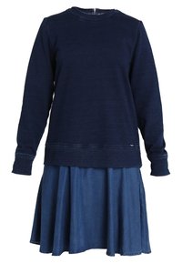 Marineblaues Sweatshirt mit rundem Halsausschnitt und gerippten Bündchen, über einem passenden Jeansrock getragen, der am Saum ausgestellt ist.