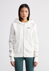 Sweatshirt branco com fecho zip, feito de um tecido macio, apresentando um capuz grande, bolsos frontais e um pequeno logo preto da Nike no lado esquerdo do peito.
