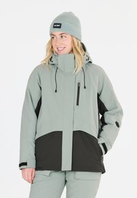 Ljusgrön vattentät jacka med en svart nederdel, justerbar huva, ficka med dragkedja fram och elastiska muddar. Matchas med byxor i samma färg.