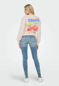 Sweatshirt rose clair avec un motif de cerise au dos. Assorti à un jean skinny bleu et des baskets blanches. Tissu doux et coupe décontractée.