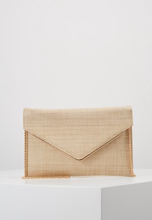 Pochette enveloppe beige texturée avec passepoil doré et bandoulière chaîne dorée sur surface blanche sur fond clair.