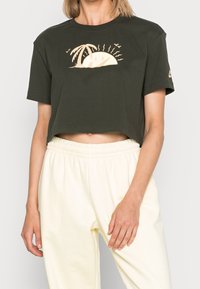 Tummanvihreä lyhythihainen puuvillapaita, jossa on kremestä värinen graafinen kuva auringosta ja palmusta. Rentoa istuvuutta.