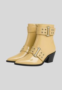 Stivaletti alla caviglia in pelle verniciata gialla con punta affusolata, cinturini alla caviglia con dettagli in fibbia e occhiello, e tacco basso nero.