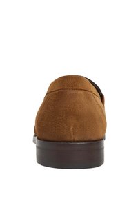 Mocassini in suede marrone con punta arrotondata, suola in gomma marrone a profilo basso e dettagli di cucitura discreti lungo la parte superiore.