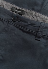 Pantaloni bleumarin cu o textură fină, având un nasture negru, detalii cusute și o etichetă țesută inscripționată "Matinique."
