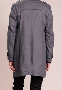 Szary, długi płaszcz o konstrukcyjnym kroju, z mankietami na guziki i tylną karczkiem. Tkanina o fakturze z gładkim wykończeniem.