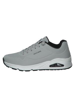 Zapatilla Skechers gris con detalles negros, diseño perforado, cierre de cordones y suela blanca acolchada con amortiguación visible de aire.