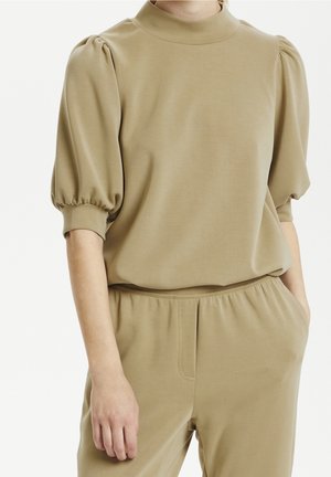 Top beige de manga corta con cuello alto y mangas abullonadas. Hecho de una tela suave con un ajuste holgado, combinado con pantalones de cintura elástica a juego.