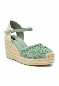 Alpargata verde bordada con cuña de yute trenzado y correa de tobillo ajustable. Presenta una puntera texturizada y un detalle de patrón sutil.