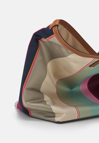 Colorful fabric tote bag with a smooth texture, featuring a multicolored minimalist pattern. Brown leather handle for easy carrying.