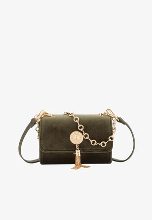 Grüne Samthandtasche mit einer goldenen Kettenriemen, die ein rundes Emblem und ein Quasten-Detail an der Front aufweist. Kompaktes rechteckiges Design.