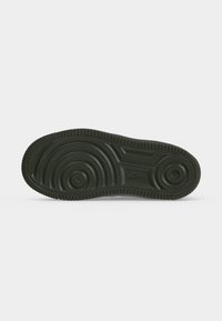 Μαύρη λαστιχένια σόλα παπουτσιού Nike με κυκλικά σχέδια πέλματος και λογότυπο Nike ανάγλυφο κοντά στο κέντρο.