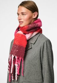 Sciarpa multicolore in tonalità di rosso e rosa, realizzata in morbido tessuto con un motivo marmorizzato e bordi frangiati, avvolta attorno al collo.