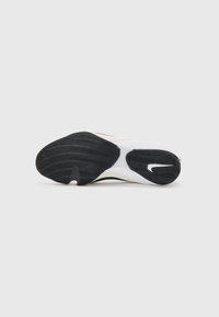 Black rubber outsole with textured grip, transitioning to a smooth white upper, featuring a subtle logo and streamlined design.