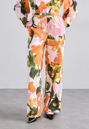 Blomsterprintede bukser med en lyserød bund, der har store orange og grønne blomster. Elastisk talje, afslappet pasform og brede ben.