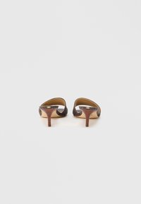 Mules de ante marrón con tacón y parte trasera abierta, con un diseño curvado y tacón de madera acanalado. Forro interior suave para mayor comodidad.