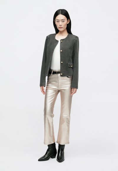 Veste en denim gris avec des boutons dorés, assortie à un pantalon métallique rose brillant et des bottines noires. Design simple, coupe ajustée.