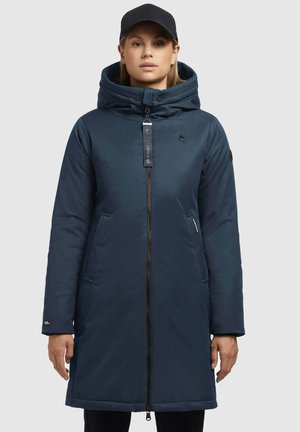 Marineblauwe lange pufferjas met een hoge kraag, rits aan de voorkant, zijzakken en een logo-accent op de borst. Zachte textuur met een getailleerde silhouette.