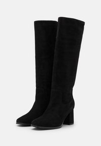 Bottes noires en daim montant jusqu'au genou, avec un bout pointu et un talon épais. Texture lisse sans ferrures ni ornements visibles.