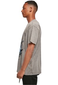 Grå bomulds t-shirt med grafisk design i blå nuancer, korte ærmer og en afslappet pasform. Slidt tekstur og let oversized form.