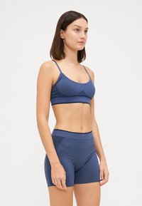 Navy blue sports bra and shorts set made of smooth fabric, featuring wide straps and textured detailing on the sides of the shorts.