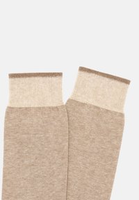 Calze beige a lunghezza ginocchio con un motivo testurizzato, caratterizzate da un bordo a coste di un tan più chiaro nella parte superiore. Tessuto morbido e lavorato a maglia.