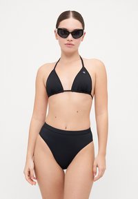 Svart bikiniset med trekantet halterneck-top og høy midje-bunn, laget av glatt stoff. Inkludert et par svarte katteøyne-solbriller.