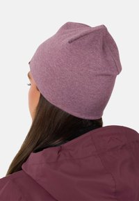 Paarse gebreide beanie met een zachte textuur, met een taps toelopende top en naadloos ontwerp. Gedragen met een bijpassende bordeauxrode jas.