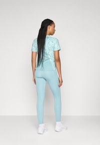 Lyseblå treningsgenser med teksturert trykk, kombinert med matchende leggings. Ensembelen har en tettsittende design og pustende materiale.