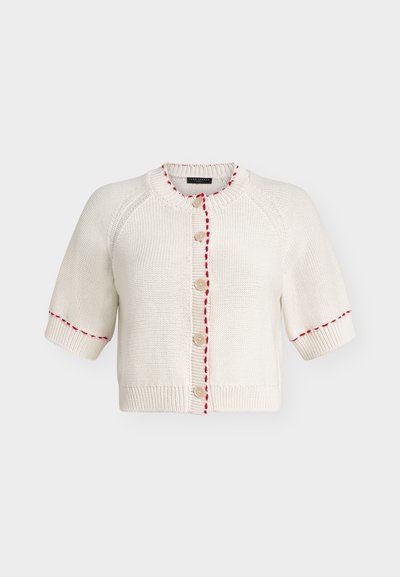 Cardigan en maille crème à manches courtes, encolure ronde, boutons beige et coutures rouges le long de la ligne des boutons et des poignets.