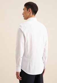 Biała koszula z długim rękawem w jasnoniebieskie pionowe paski, z guzikami na mankietach i klasycznym kołnierzykiem, z wyprofilowanym dołem i gładką teksturą materiału.