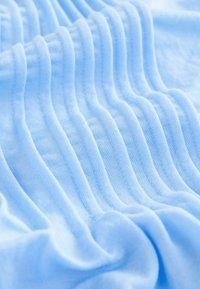 Tissu bleu clair doux avec une texture fine en maille et des plis espacés uniformément créant un motif ondulé à la surface.