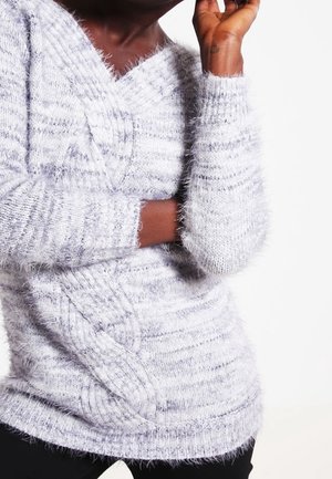 Suéter de punto gris claro con cuello en V, que presenta un diseño de trenzas y un hilo texturizado y suave. Mangas largas con puños acanalados.