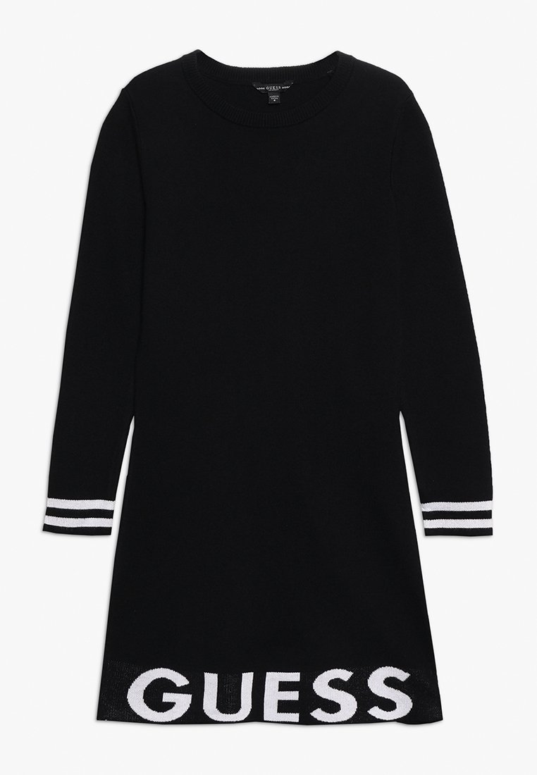 Musta neulemekko pitkähihaisilla ja pyöreällä kaula-aukolla. Ominaisuuksiin kuuluu valkoiset raidalliset yksityiskohdat hihoissa ja "GUESS"-logo helmassa.