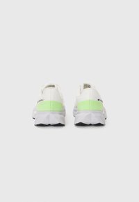 Baskets de sport blanches avec une tige en mesh texturé, accent vert au talon et une semelle extérieure grise géométrique. Design léger.