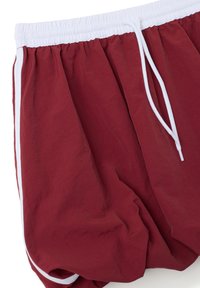 Pantaloni corti bordeaux con coulisse bianca, dotati di una vita elasticizzata e strisce laterali. Tessuto leggero e stropicciato con una vestibilità ampia.