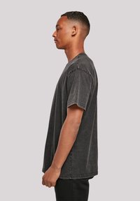 Charcoal grey oversized T-shirt made of cotton, featuring a crew neckline, short sleeves, and visible stitching details.