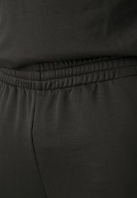 Czarne spodenki sportowe z elastycznym pasem i gładkim materiałem, o dopasowanym kroju i minimalnej liczbie szwów dla komfortu.