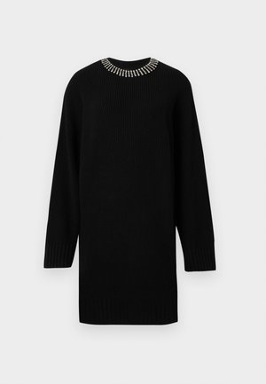 Svart strikket kjole med lange ermer, prydet med en halslinning med rhinstein. Ribbete tekstur gjennom hele plagget, avslappet passform med rund kant.
