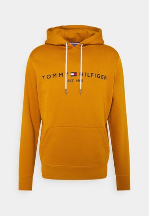 Haut à capuche jaune avec une poche kangourou à l'avant, un cordon de serrage et le texte de marque "TOMMY HILFIGER EST. 1985" en noir et blanc.