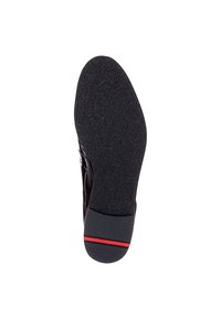 Semelle de chaussure noire avec une surface texturée, une forme arrondie, en caoutchouc, et une bande accent rouge près du talon.