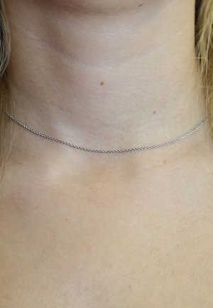 Silberne Kettenchoker-Halskette, die auf einem nackten Hals ruht, mit einem zarten, minimalistischen Design und gleichmäßig angeordneten Gliedern.