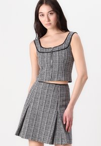 Ensemble de deux pièces comprenant un haut court sans manches et une jupe plissée. Fabriqué en tissu texturé bleu marine et blanc avec des finitions noires.